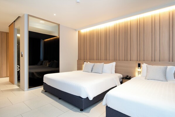 Una habitación de hotel moderna con dos camas, un vestidor y un panel de pared de madera.