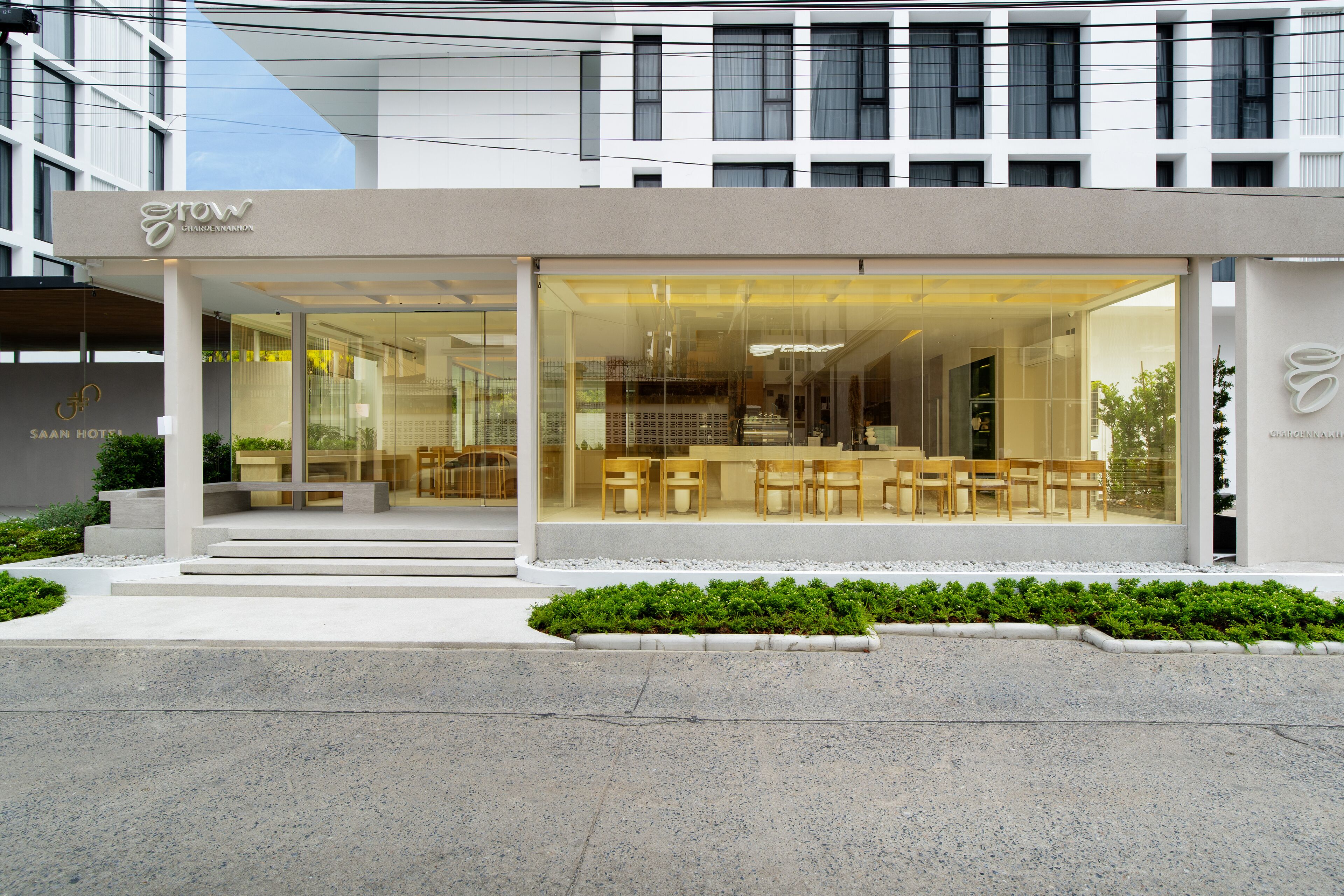 A modern hotel with a glass facade, outdoor seating area, and a visible staircase leading to the entrance.