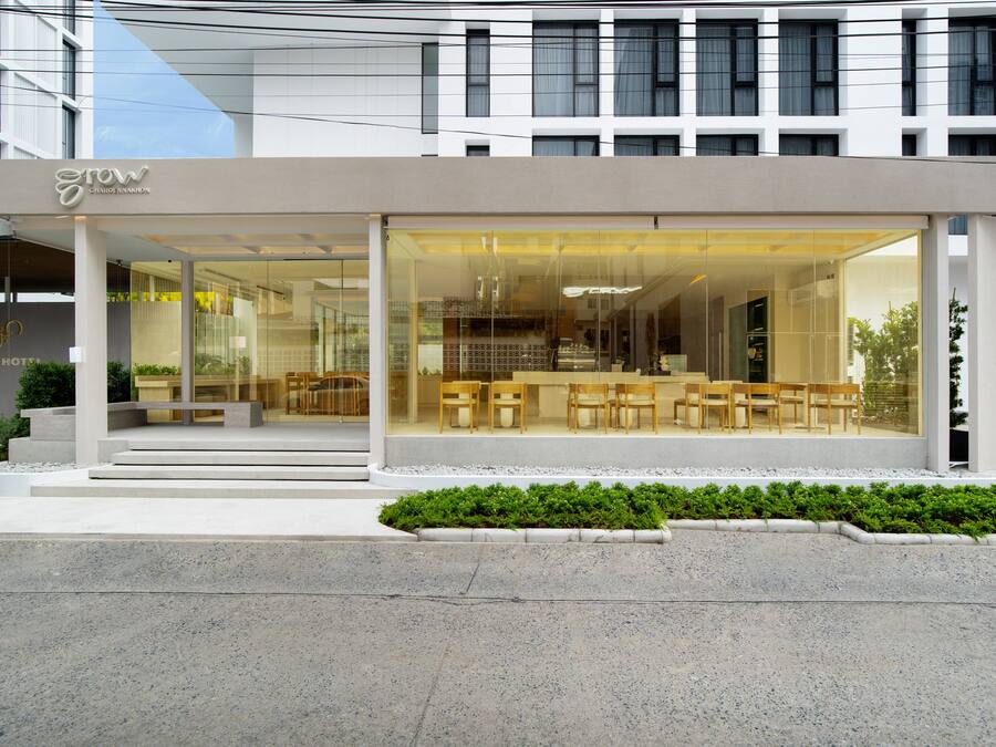 A modern hotel with a glass facade, outdoor seating area, and a visible staircase leading to the entrance.