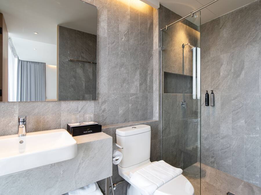 Un baño moderno con un espejo grande, un lavamanos, un inodoro y cabina de ducha con mampara de vidrio.