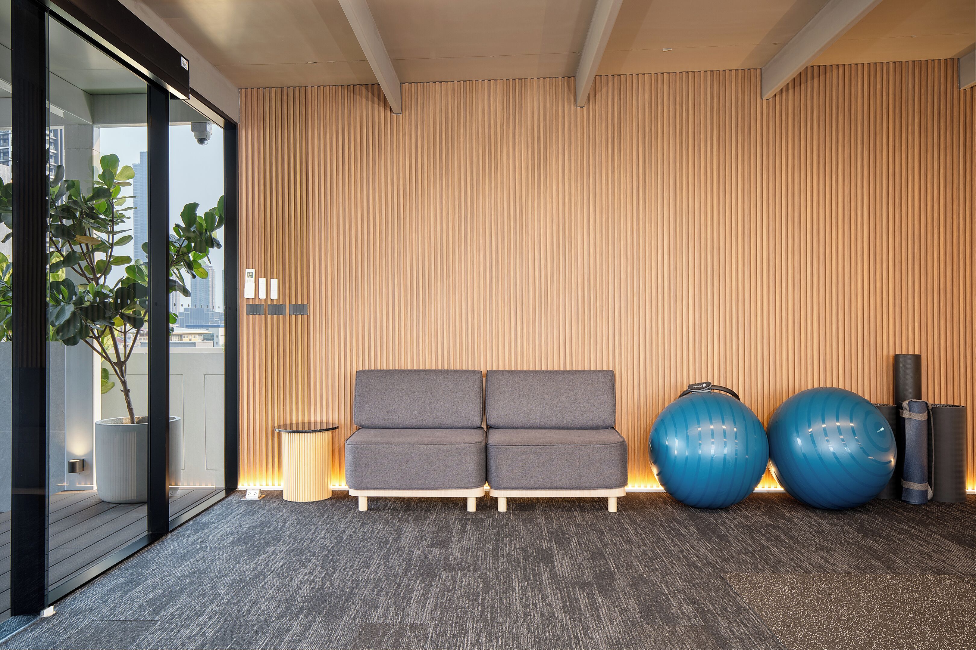 A modern waiting area with a grey sofa, two large exercise balls, and a small table.