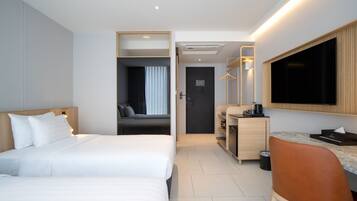 Habitación de hotel con dos camas, un escritorio, un espejo y un televisor.