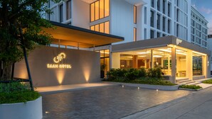 Een modern hotel met een opvallende ingang, een goed verlichte gevel en een aangelegde buitenruimte.