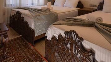 A hotel room with two beds, a patterned rug, a wooden headboard, a chandelier, a painting, and a stone wall.