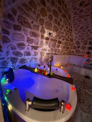 A stone-walled room with a bathtub, a bottle, and glasses. - ARUR KONAGI (Mardin)