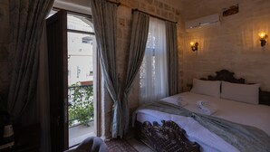 A bedroom with a large bed, curtains, a chandelier, an air conditioning unit, and a view of the outside. - ARUR KONAGI (Mardin)