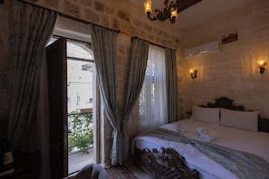 A bedroom with a large bed, curtains, a chandelier, an air conditioning unit, and a view of the outside. - ARUR KONAGI (Mardin)