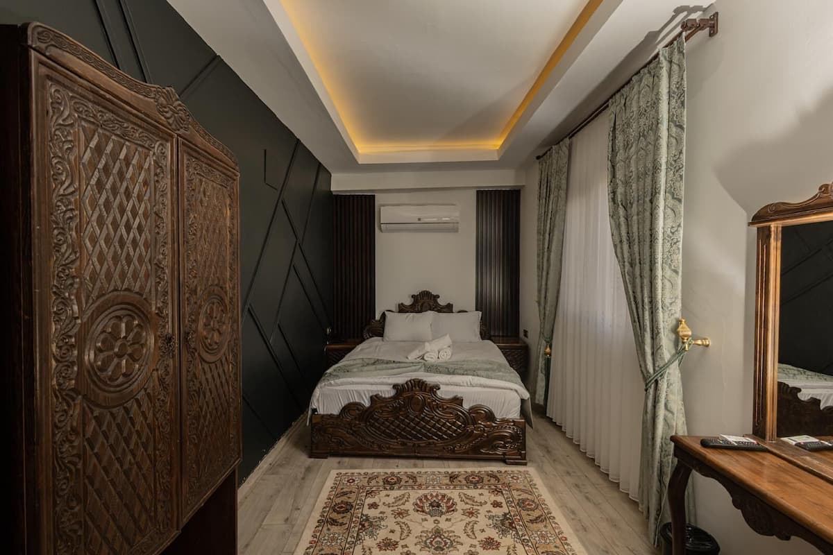 Une chambre à coucher avec un grand lit, une armoire en bois, un miroir et un tapis à motifs.