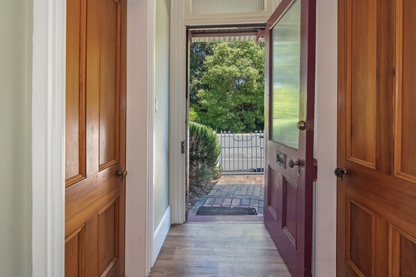 A wooden hallway leading to a door with a metal gate outside. - Birdsong Cottage (Nelson)