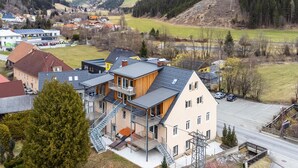 Ein mehrstöckiges Wohngebäude im modernen Stil, mit Balkonen und einer Treppe, die zum Eingang führt.