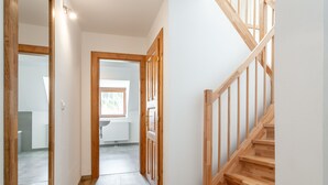 Ein Flur mit einer Holztreppe, einem Heizkörper und einem Fenster.