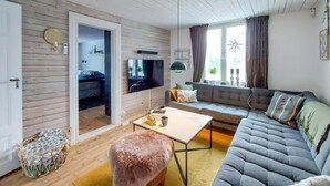 Een moderne woonkamer met een bank, salontafel en een zachte poef.