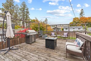 A wooden deck with a grill, a fire pit, and outdoor furniture. - Spacious Spokane retreat—5BR, sleeps 10, with fireplace, deck BBQ & pool table. (Spokane)