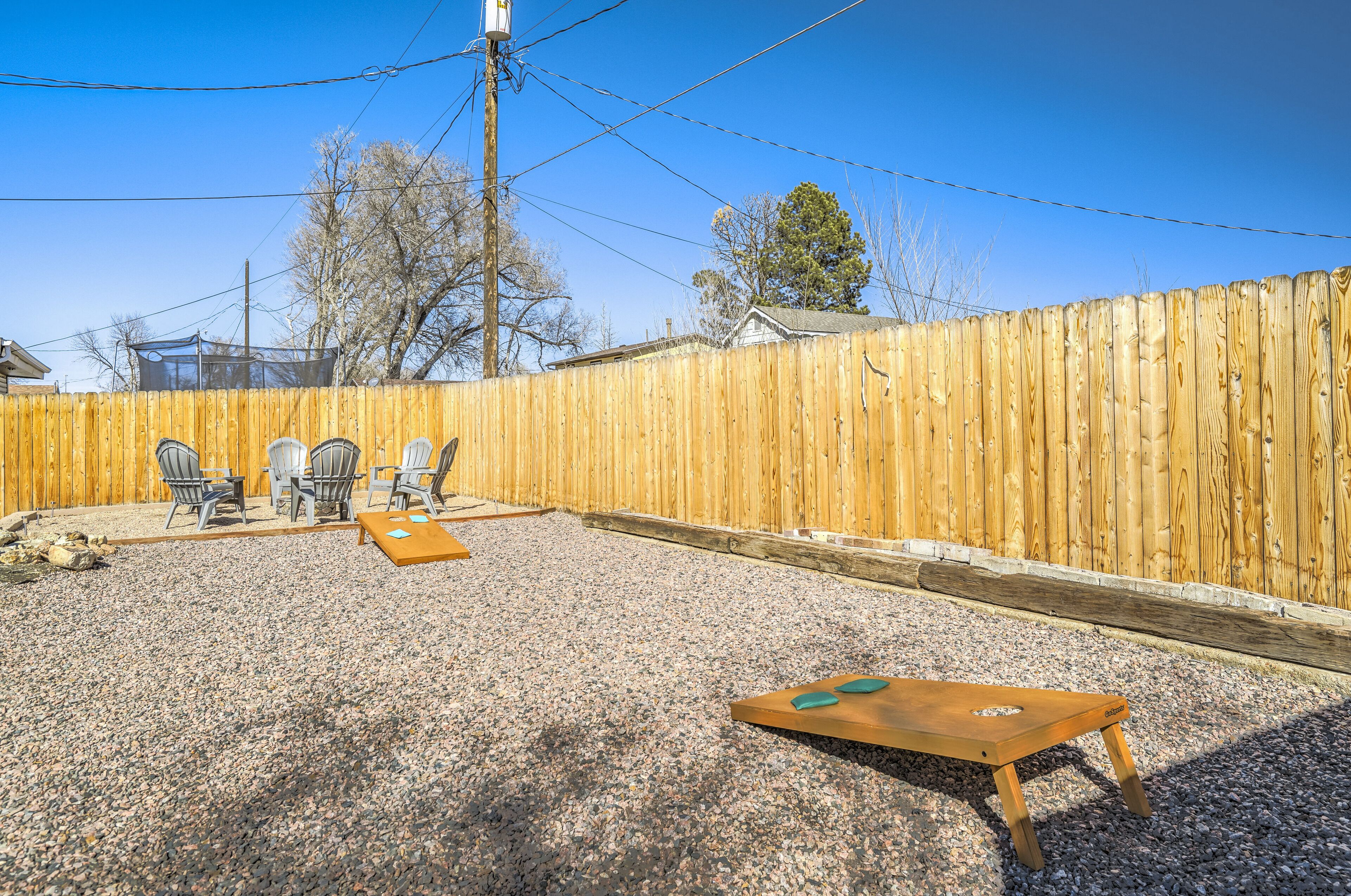 A backyard with a wooden fence, a gravel patio, and outdoor furniture including chairs and a table.