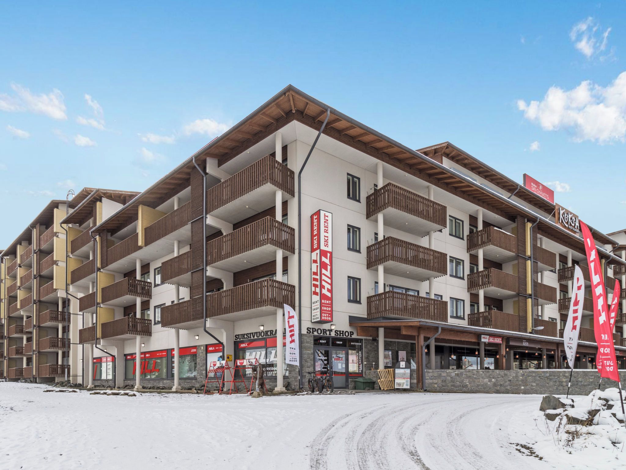 A multi-story hotel with balconies, ski rental signs, and a sport shop.