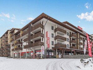 Un hôtel à plusieurs étages doté de balcons, d’enseignes indiquant un service de location de matériel de ski et d’un magasin d’articles de sport.