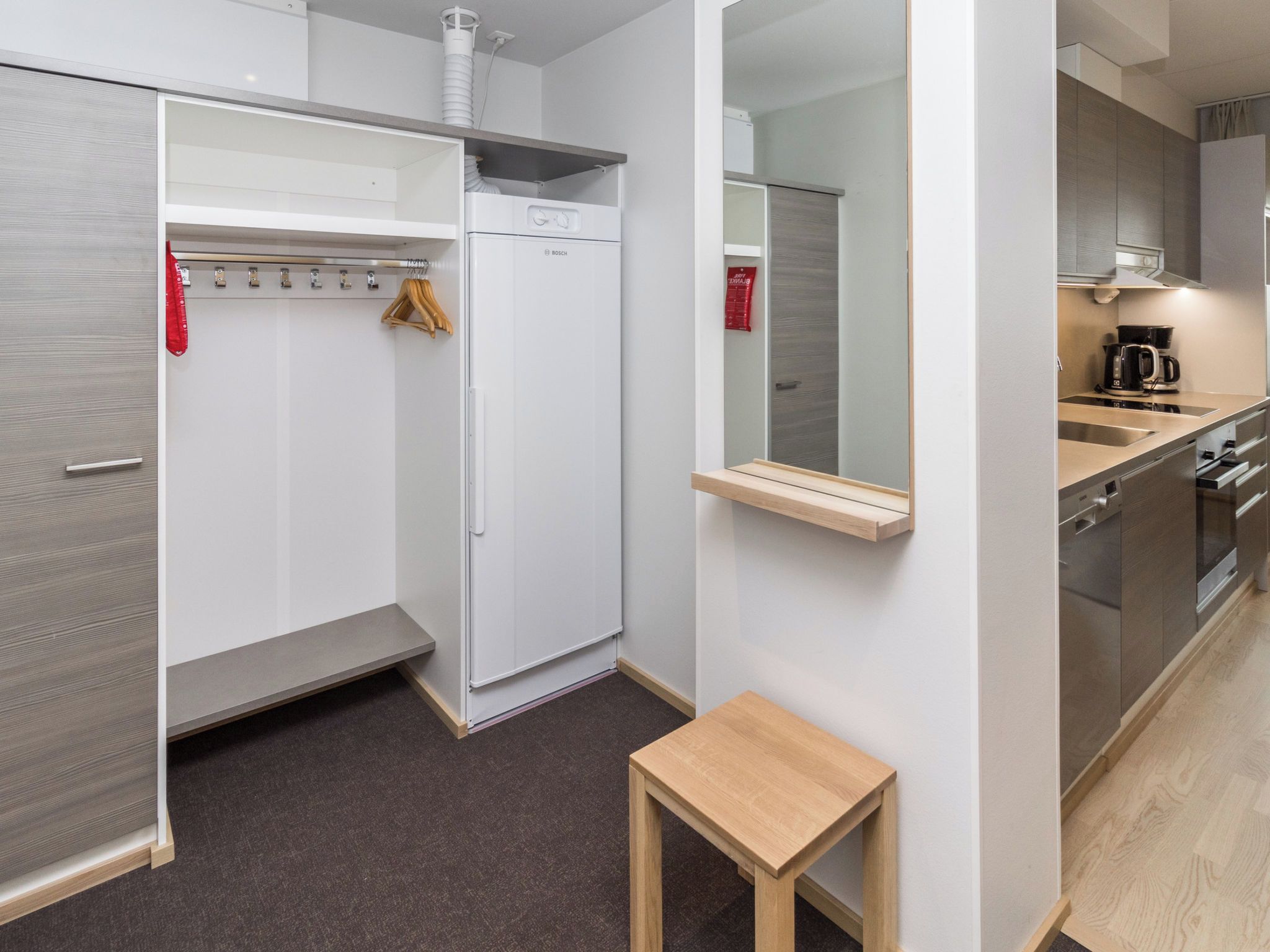 A modern kitchen with a built-in oven, a coffee maker, and a wooden table.