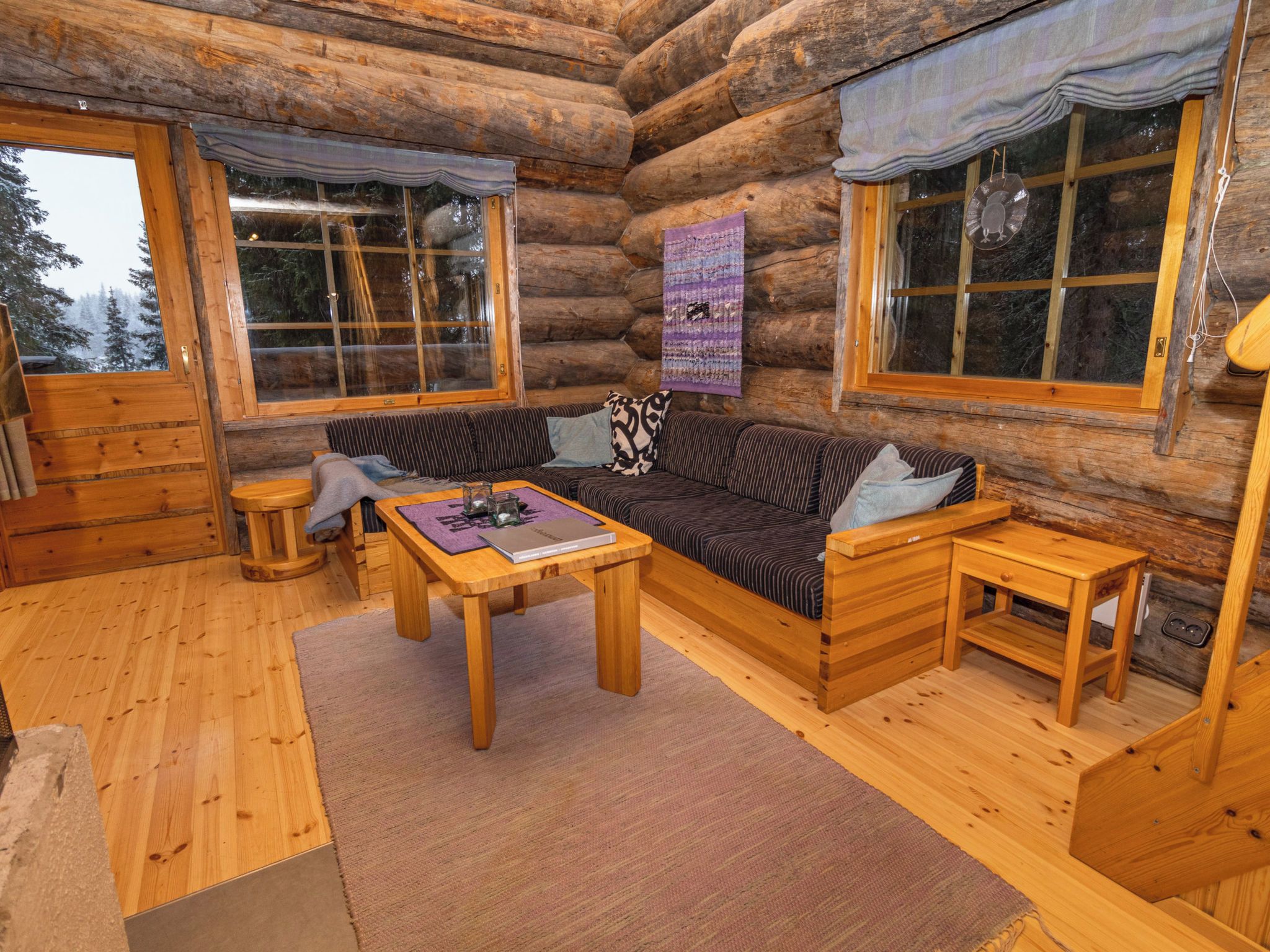 A log cabin interior with a sofa, a coffee table, and a wooden bench.