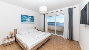 Une chambre moderne avec un grand lit, une vue sur la mer et un balcon.