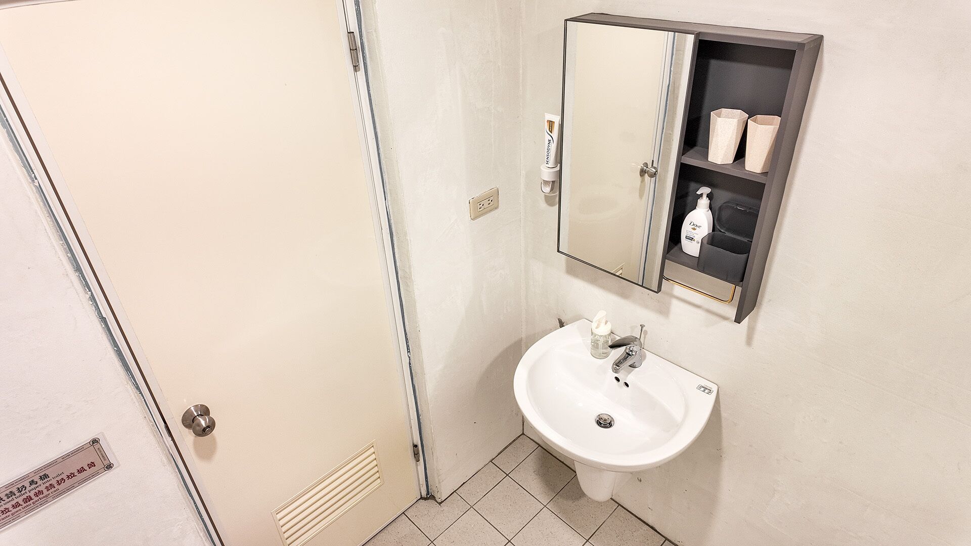 A bathroom with a white sink, a mirror cabinet, and a shower door.