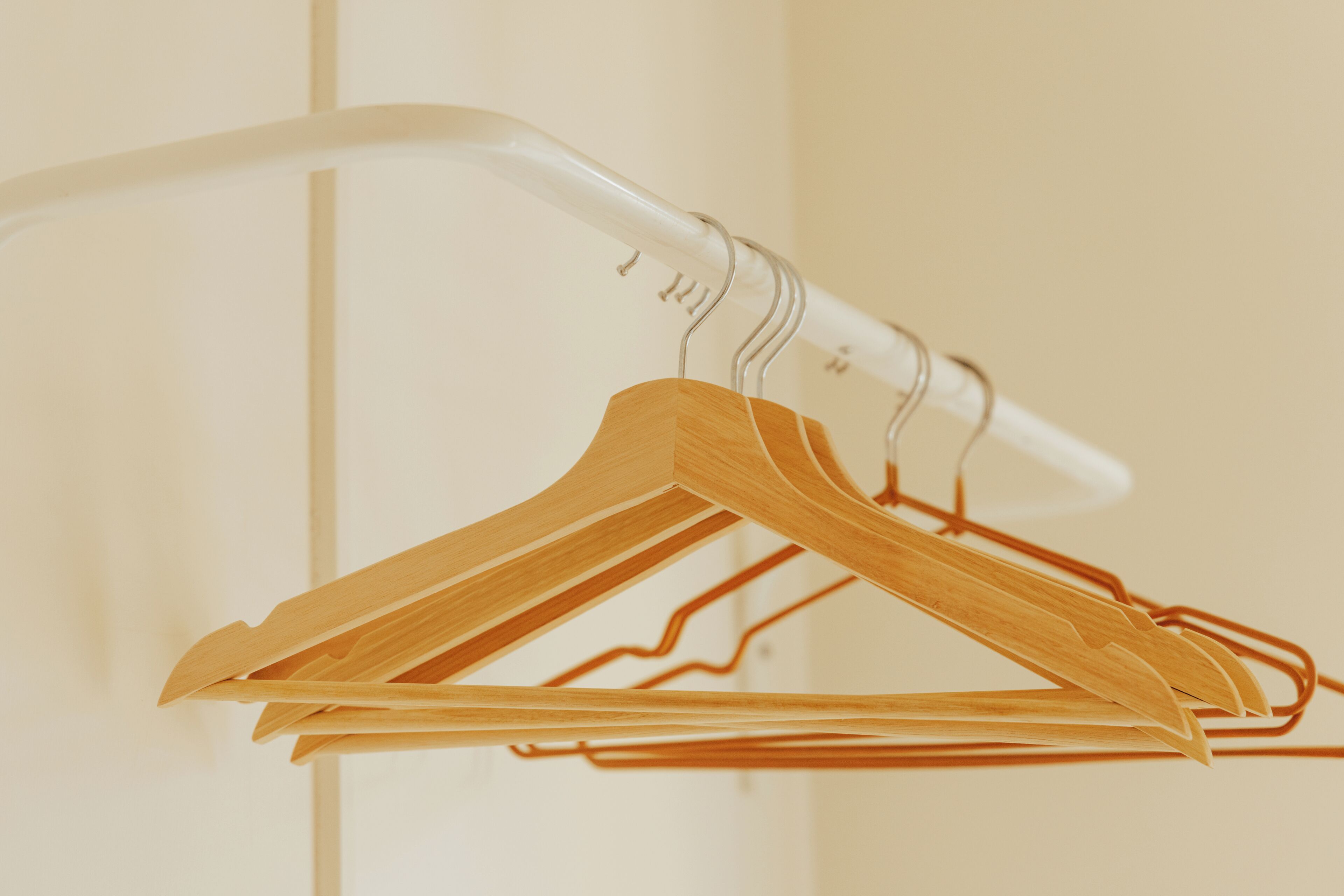 A white metal hanger rack with wooden hangers.