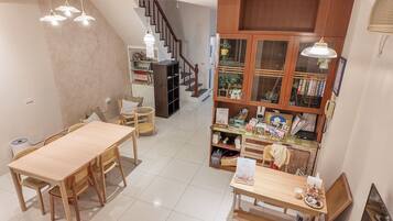 A dining area with a wooden table and chairs, a staircase, and a glass-fronted cabinet with various items.