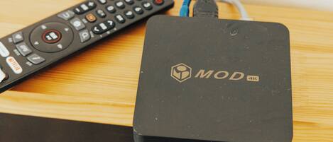 A black MOD 4K device with a remote control beside it on a wooden surface.