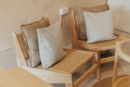 A wooden chair with a woven seat and backrest, accompanied by a cushion.. Maybe Homestay