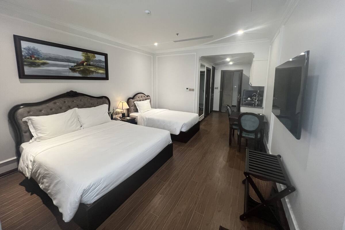 Habitación de hotel con dos camas, un comedor y un televisor.
