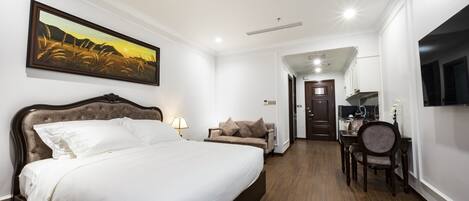 Habitación de hotel con una cama grande, un sofá, una mesa de comedor y un televisor montado en la pared.