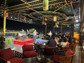 Ein Restaurant mit einer Bühne für Live-Musik, roten Sitzgelegenheiten und einer dekorativen Decke.