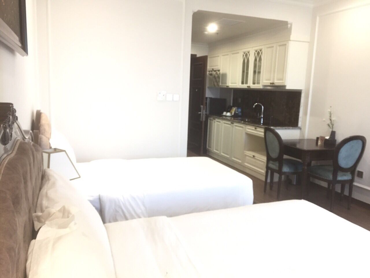 Habitación de hotel con dos camas, una kitchenette pequeña y un comedor.