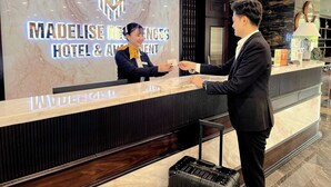 A reception desk at the Madelise Residence Hotel & Apartment with a marble counter and a modern logo.