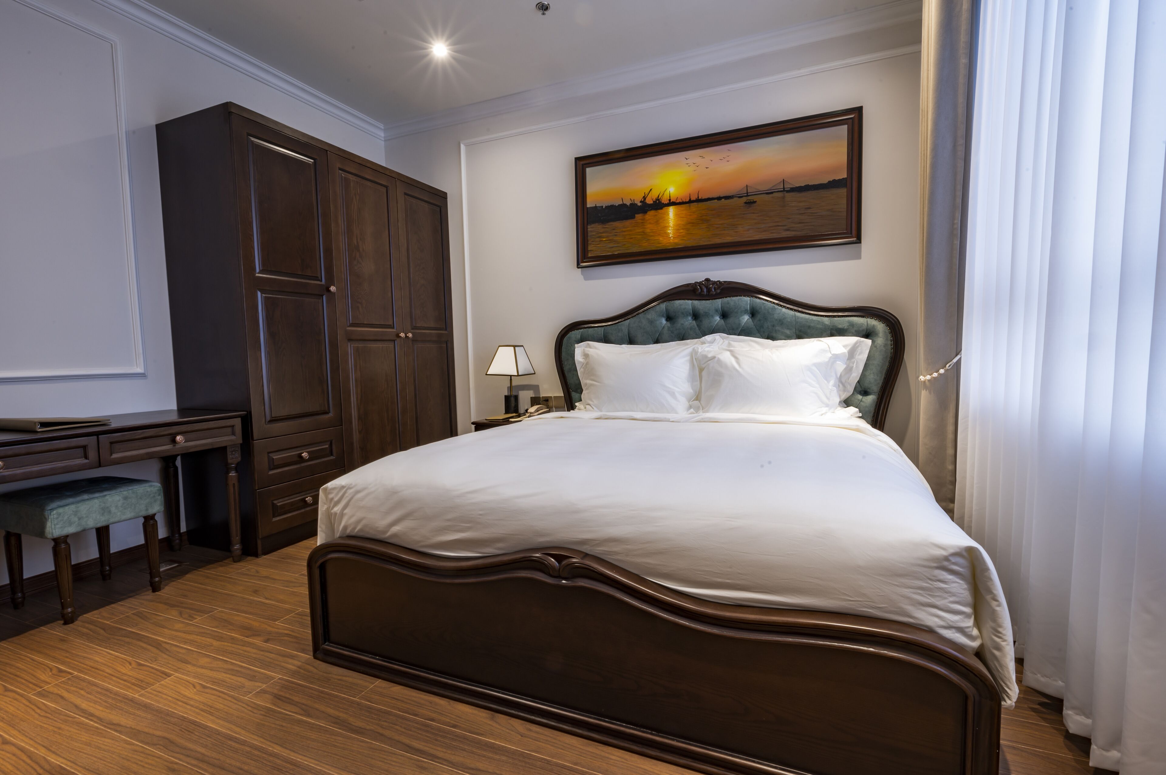 A neatly arranged bedroom with a large bed, a desk, and a wardrobe.