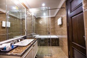 Ein modernes Badezimmer mit einer Glaskabine zur Dusche, einem großen Spiegel, einem Waschbecken und einer Badewanne.