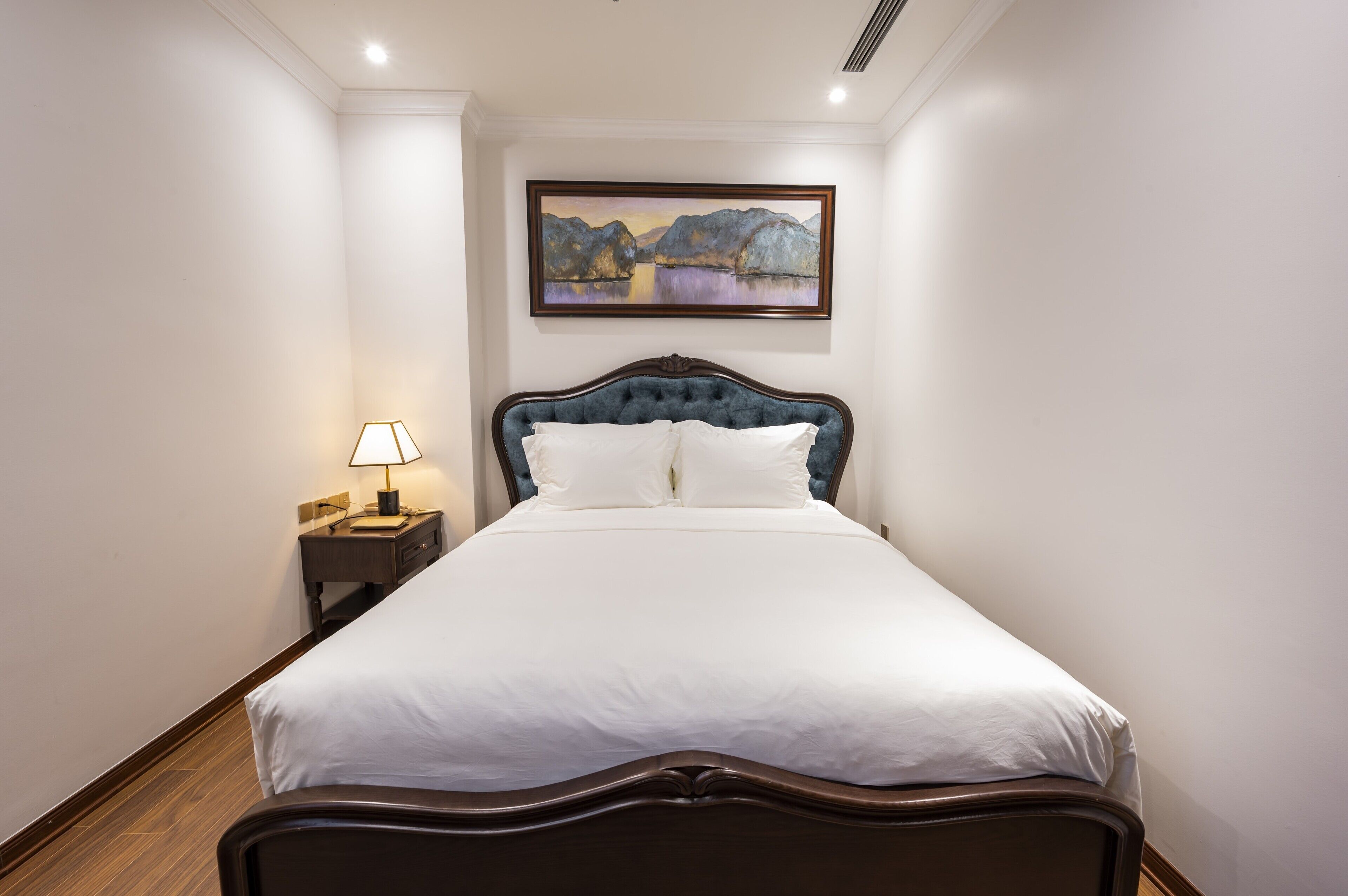 A neatly made bed with white linens in a hotel room.