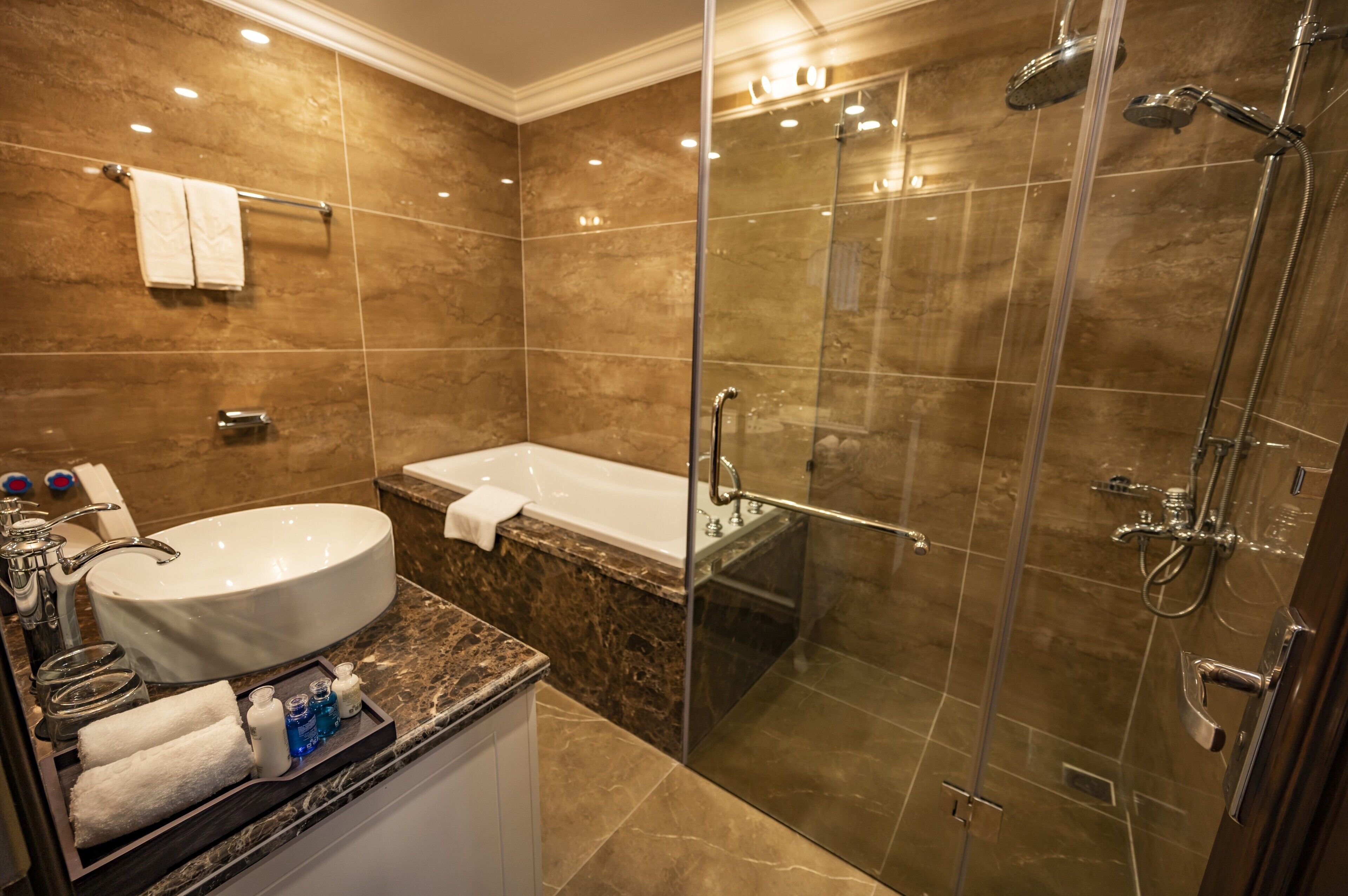 Un baño moderno con una bañera grande, cabina de ducha con paredes de vidrio y encimera de mármol.