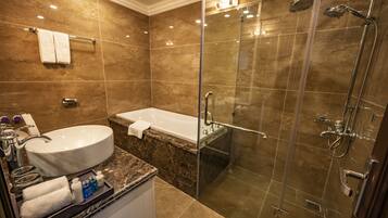 Un baño moderno con una bañera grande, cabina de ducha con paredes de vidrio y encimera de mármol.