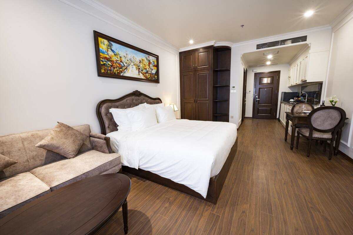 Una habitación de hotel con cama, sofá, mesa de comedor con sillas y zona de cocina.