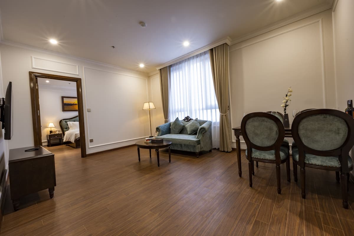 Un salón amplio con suelo de madera, un sofá, una mesa de centro y dos sillones.