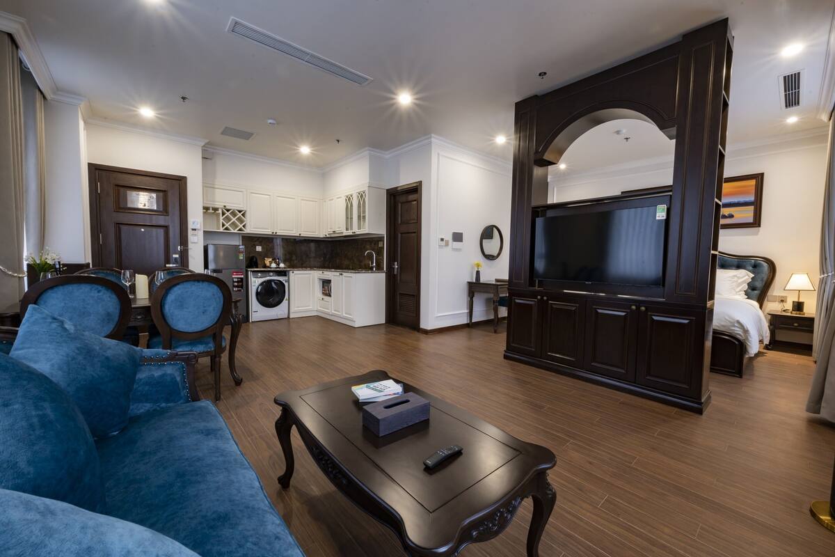 Una sala moderna con un sofá azul, una mesita de centro y un televisor en un mueble de madera oscura.