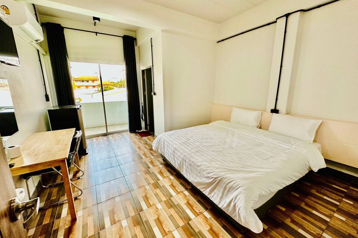 A hotel room with a bed, a desk, and a view of the outside.