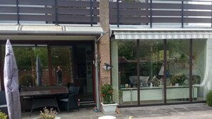Une maison moderne dotée d’un patio, d’un espace de détente extérieur abrité et d’une grande baie vitrée.
