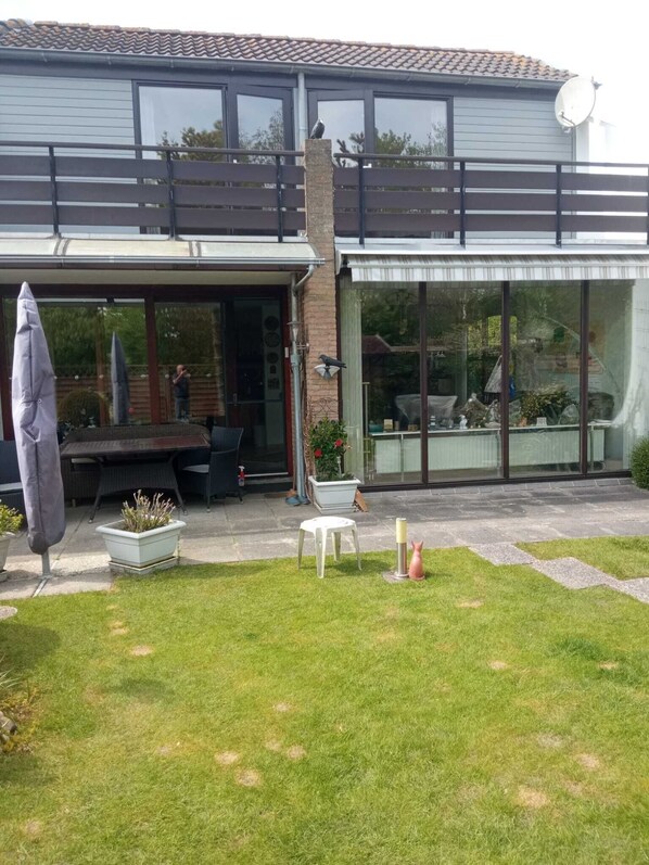 A modern house with a patio, a covered outdoor seating area, and a large glass window.
