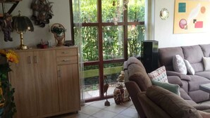 Un salon avec un canapé, un meuble en bois et une grande fenêtre donnant sur un paysage verdoyant.