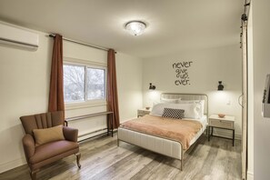 A bedroom with a bed, a chair, a window with curtains, a wall with a motivational quote, and a ceiling light. - Great for Couples or Family in Niagara Wine Country (Lincoln)