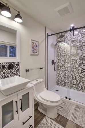 A bathroom with a white sink, toilet, and shower with patterned tiles. - Great for Couples or Family in Niagara Wine Country (Lincoln)