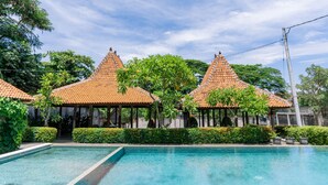 A swimming pool with a tiled roof structure in the background. - Bali Desa Asri (Keroboken Kelod)