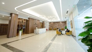 Un moderno vestíbulo de hotel con un mostrador de recepción, zona de estar y un amplio muro de cristal.