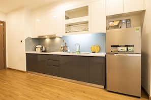A modern kitchen with a stainless steel refrigerator, a built-in oven, and a microwave.
